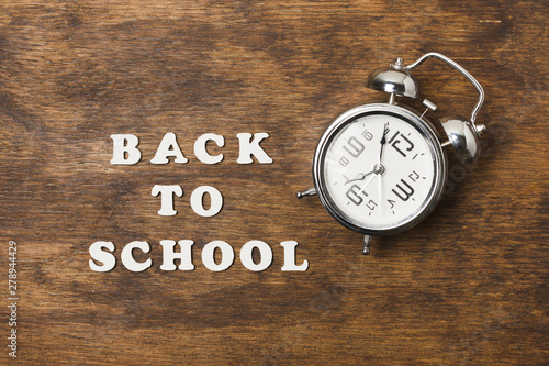 Back to school concept with clock on wooden background