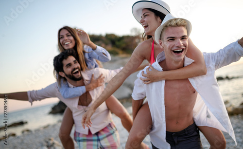 Cheerful friends enjoying weekend and having fun on beach