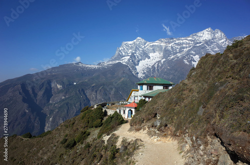 Himalayas mountains landscape with trail to guest house hidden half behind green hill and view of Kongde mountain