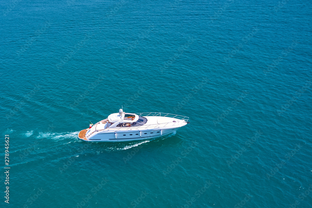The yacht is white at high speed moving against the background of turquoise waters. Side view. Aerial photography with drone. The yacht is white at high speed moving against the background of turquoise waters. Side view. Aerial photography with drone.