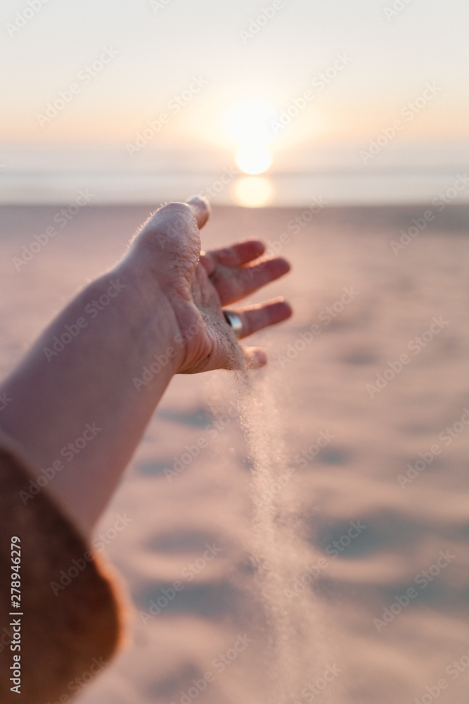 A woman feeling the sand between her fingers A woman feeling the sand between her fingers