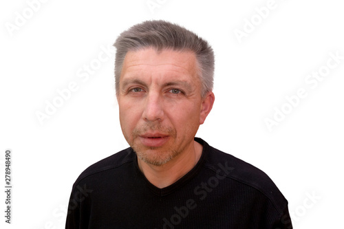 Guy looks into camera and squints. Isolated full faced portrait on white background. Emotion and gesture of middle aged unshaven shaggy man in black t-shirt. Angry face and aggressive view