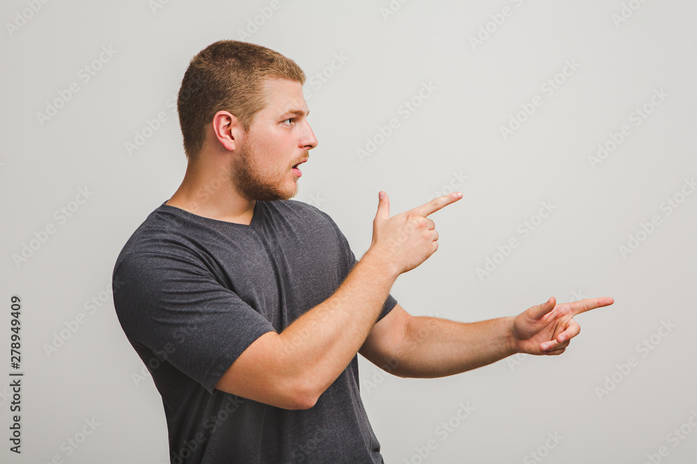 Portrait of handsome young man pointing finger to an empty copy space Portrait of handsome young man pointing finger to an empty copy space