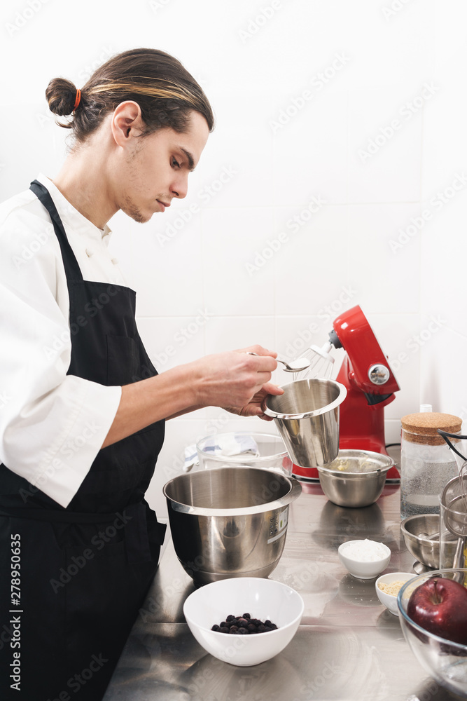 Handsome young cook chef at the kitchen cooking indoors. Handsome young cook chef at the kitchen cooking indoors.