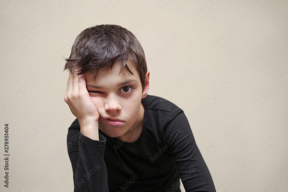 Portrait of the tired boy of the European appearance on a light background. Portrait of the tired boy of the European appearance on a light background.
