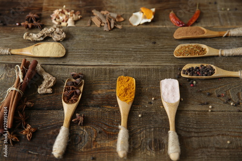 traditional spices: turmeric, ginger, cinnamon, nutmeg, pepper, pink salt, star anise in wooden spoons on a wooden background lemongrass, orange peel cinnamon sticks. With copy space for text or image