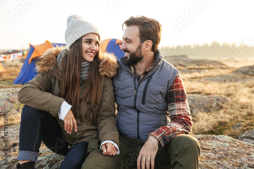 Happy young loving couple outside with tent in free alternative vacation camping over mountains.