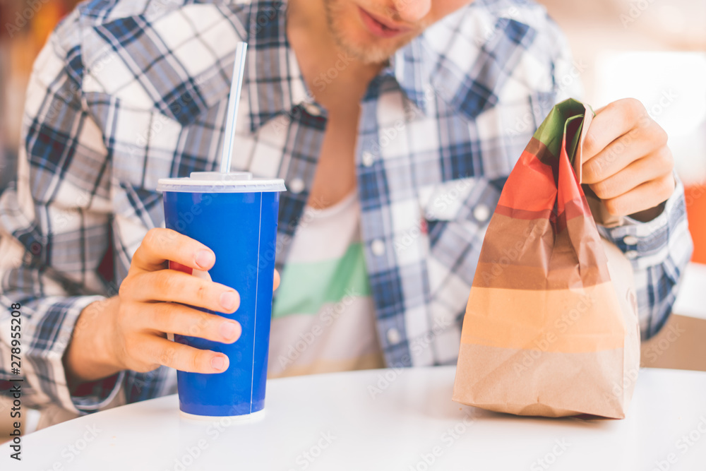 person holding a fast food package and glass with lunch in public person holding a fast food package and glass with lunch in public