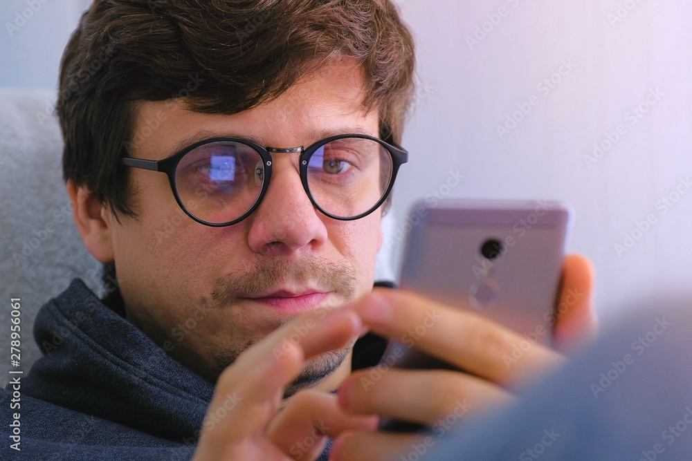 Man in glasses buy in online shop and browsing on smartphone. Face close-up. Online shopping