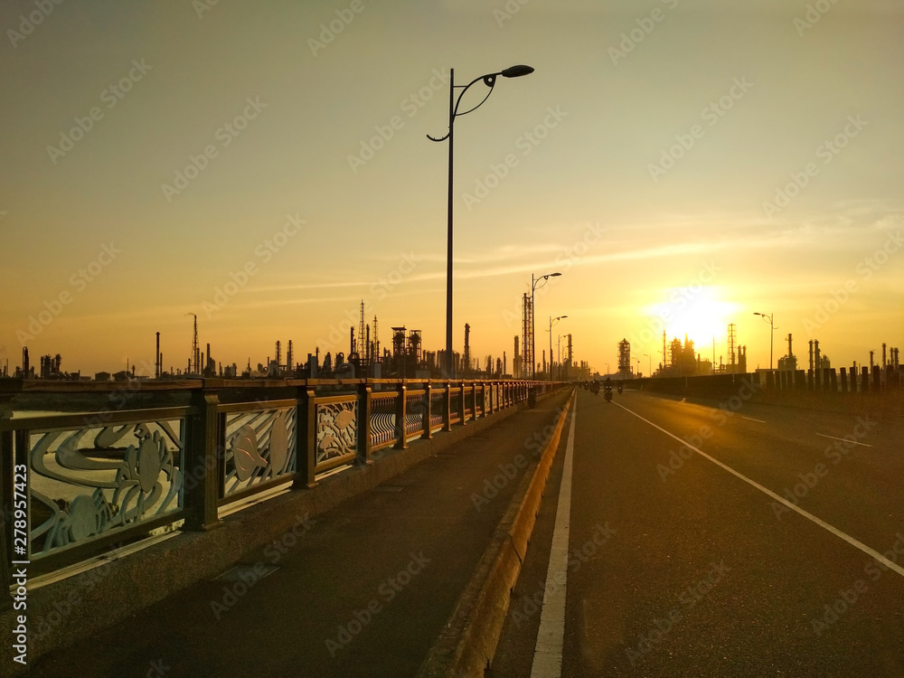 Sunset over bridge and industrial city with factories in background
