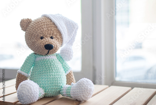 Handmade amigurumi teddy bear on wooden table