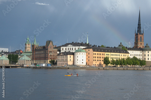 Beautiful scenic panorama of the Old City (Gamla Stan) cityscape pier architecture with historic town houses with colored facade, water, rainbow and a cloudy Sky in Stockholm, Sweden.