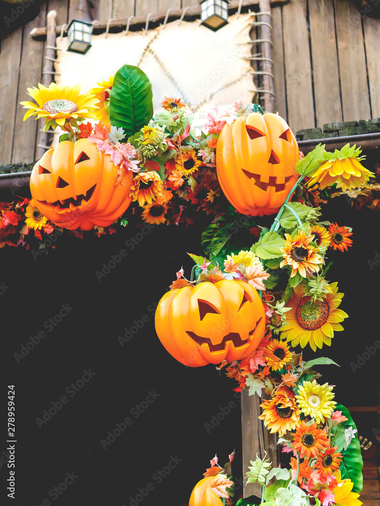 Obraz premium Halloween pumpkins with autumn flowers and decorations outside a house. Family fun activity, carved pumpkins into jack-o-lanterns for halloween.