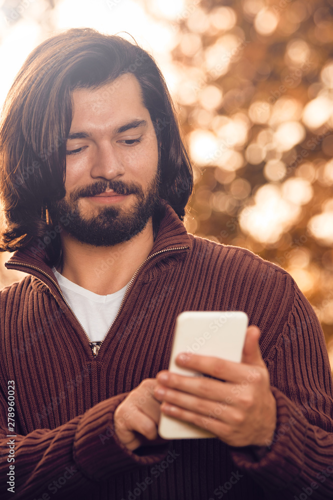 Modern man using cellphone in the autumn colored park. Modern man using cellphone in the autumn colored park.