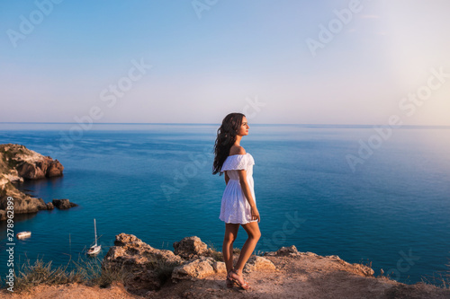 Young beautiful woman on the rock in the sea.