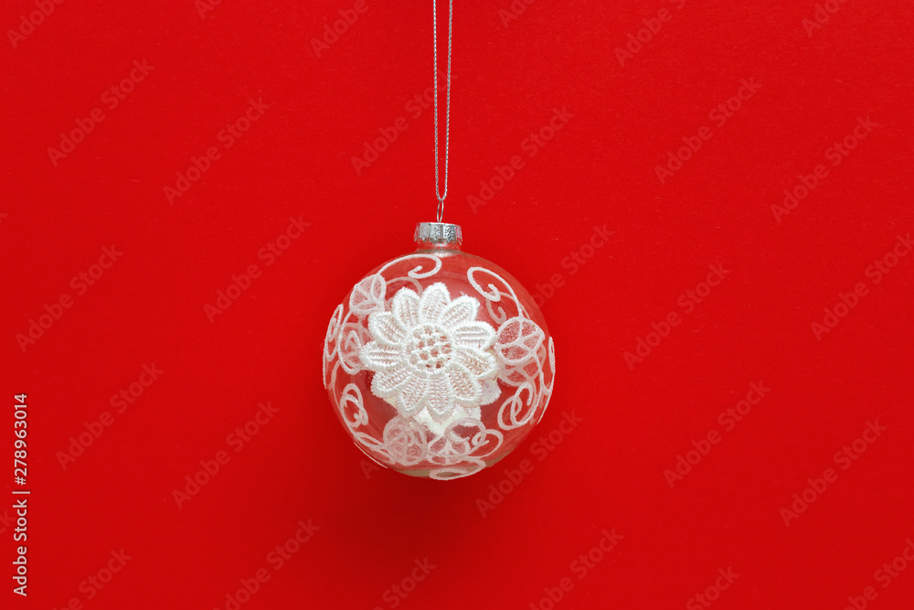 New Year glass ball transparent with white lace snowflake on red paper background. Creative holiday christmas concept. Minimalism. New Year glass ball transparent with white lace snowflake on red paper background. Creative holiday christmas concept. Minimalism.