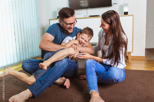 Smiling young parents and their child are very happy, they are at home