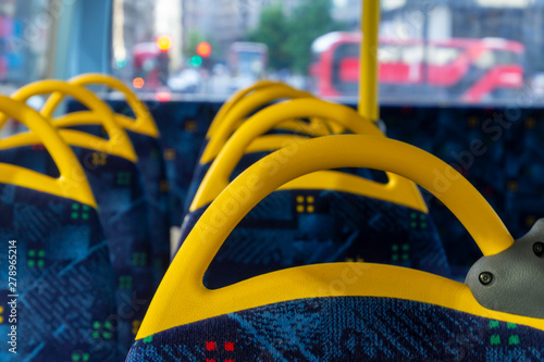 Inside a double decker bus empty seats. Interior with yellow and blue chairs and seats.
