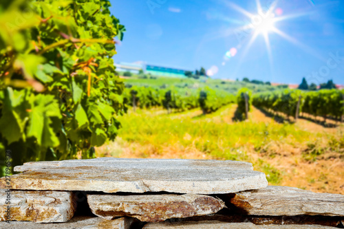 Stones and stone tray background in the beautiful sunny vineyard view and sun rays in distance