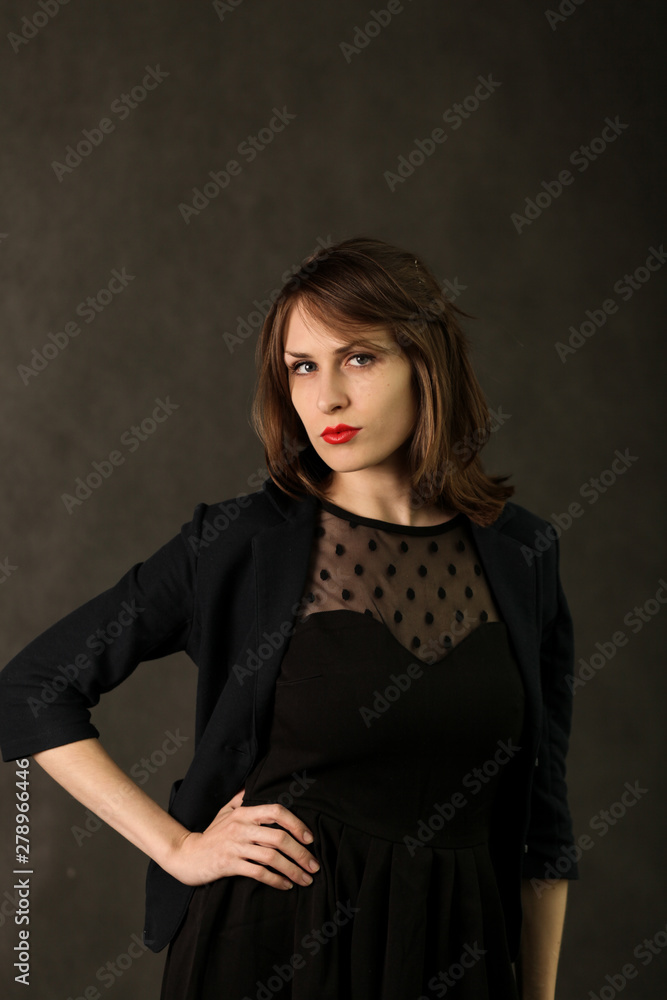 Portrait of a young woman in the Studio. Daring brunette with red lipstick on her lips posing.