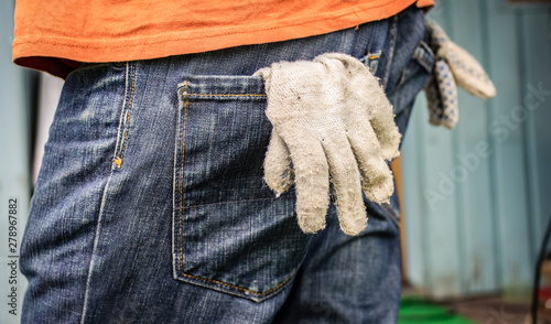 Working protective gloves in the jeans pocket close up photo