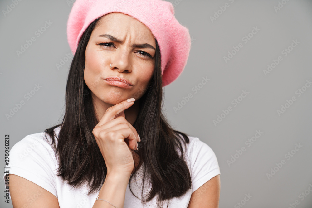 Thinking sad young french woman in beret posing isolated over grey wall background. Thinking sad young french woman in beret posing isolated over grey wall background.
