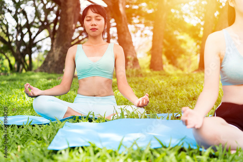 student university or two Asian young women friends doing exercise or Practicing yoga outdoor. vital, meditation at fitness lifestyle club midst of peaceful nature. zen, health,international yoga day