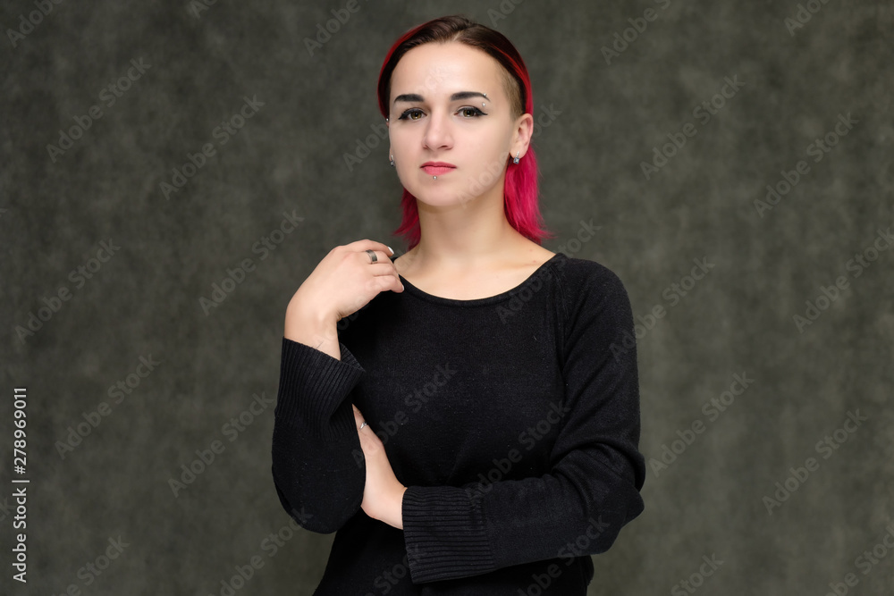 Portrait to the waist of a pretty girl with red hair on a gray background in a black jacket. Standing right in front of the camera in a studio with emotions, talking, showing hands, smiling Portrait to the waist of a pretty girl with red hair on a gray background in a black jacket. Standing right in front of the camera in a studio with emotions, talking, showing hands, smiling
