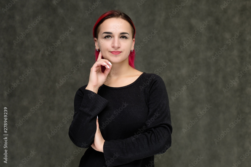 Portrait to the waist of a pretty girl with red hair on a gray background in a black jacket. Standing right in front of the camera in a studio with emotions, talking, showing hands, smiling Portrait to the waist of a pretty girl with red hair on a gray background in a black jacket. Standing right in front of the camera in a studio with emotions, talking, showing hands, smiling