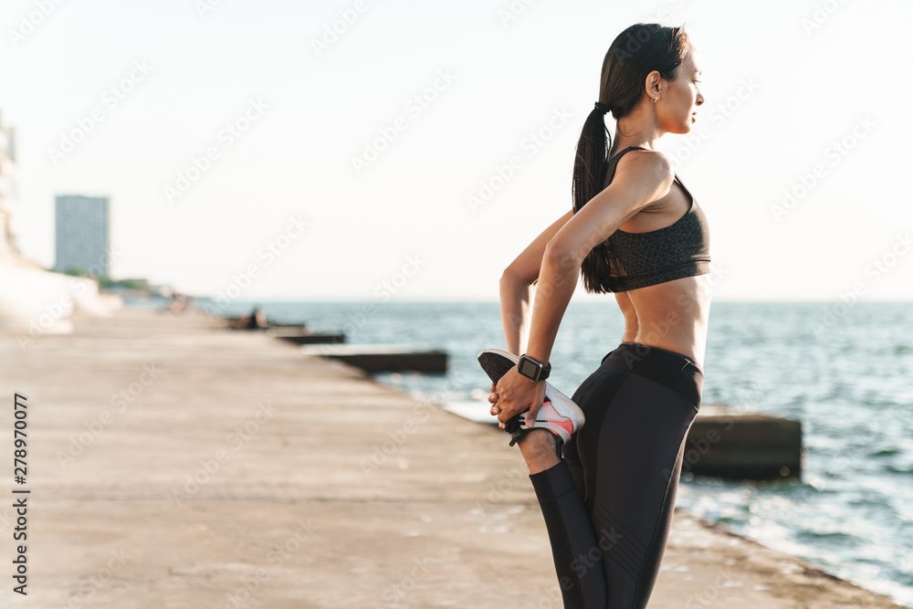 Young strong fitness woman outdoors at the beach at morning make stretching exercises. Young strong fitness woman outdoors at the beach at morning make stretching exercises.