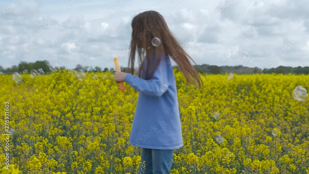 A child with soap bubbles. A cute little girl is having fun with soap bubbles on a yellow flowering field. A child with soap bubbles. A cute little girl is having fun with soap bubbles on a yellow flowering field.
