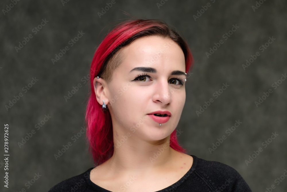 Close-up Portrait of the shoulders of a pretty girl with red hair on a gray background in a black jacket. Standing directly in front of the camera in the studio with emotions, talking, smiling. Close-up Portrait of the shoulders of a pretty girl with red hair on a gray background in a black jacket. Standing directly in front of the camera in the studio with emotions, talking, smiling.