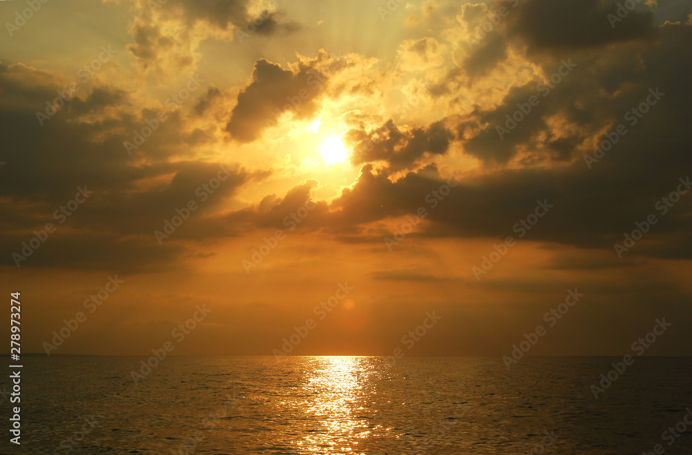 Beautiful cloudy sunset over the sea with the beams shining through the clouds