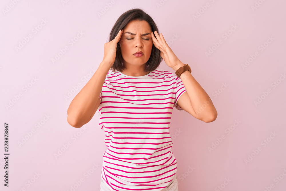 Young beautiful woman wearing striped t-shirt standing over isolated pink background with hand on headache because stress. Suffering migraine. Young beautiful woman wearing striped t-shirt standing over isolated pink background with hand on headache because stress. Suffering migraine.