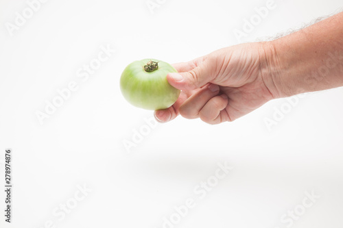 Tomate en la mano de una persona adulta. Tomate sobre fondo blanco y en la mano derecha de un ser humano. Tomate saludable, ecológico preparado para ser vendido o comido o cocinado.