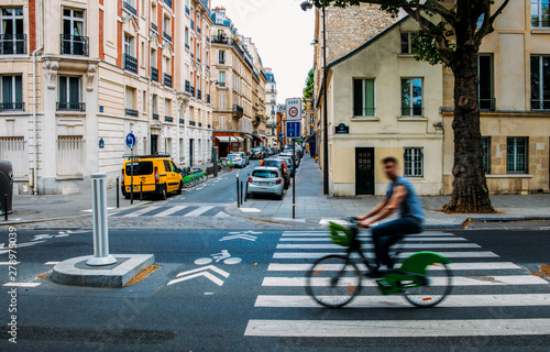 Fototapeta Naklejka Na Ścianę i Meble -  Unidentifiable man cycling down the street. The public bike system in Paris