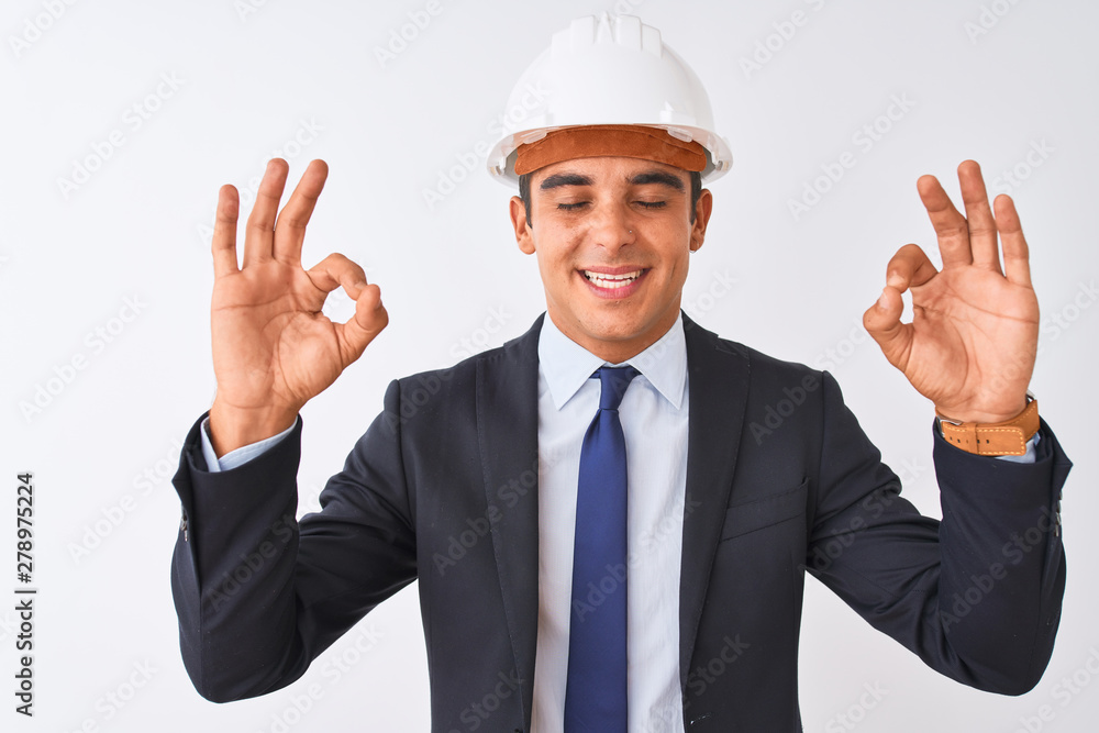 Young handsome architect man wearing suit and helmet over isolated white background relax and smiling with eyes closed doing meditation gesture with fingers. Yoga concept.