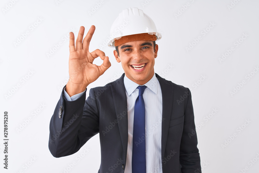 Young handsome architect man wearing suit and helmet over isolated white background smiling positive doing ok sign with hand and fingers. Successful expression. Young handsome architect man wearing suit and helmet over isolated white background smiling positive doing ok sign with hand and fingers. Successful expression.