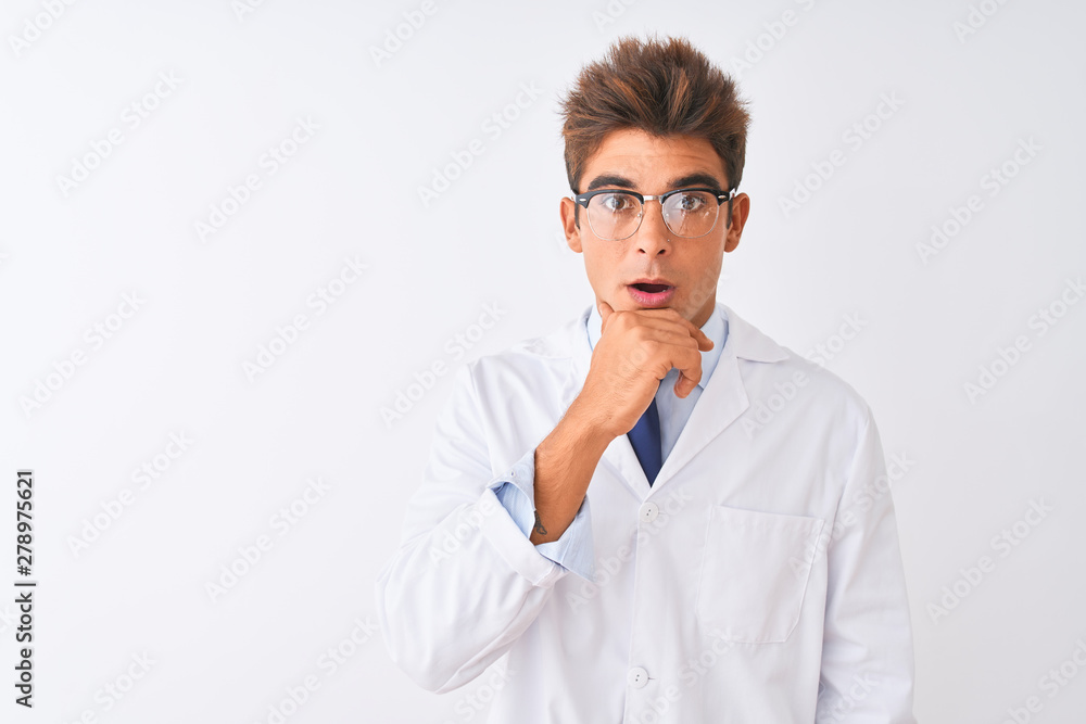 Young handsome sciencist man wearing glasses and coat over isolated white background Looking fascinated with disbelief, surprise and amazed expression with hands on chin