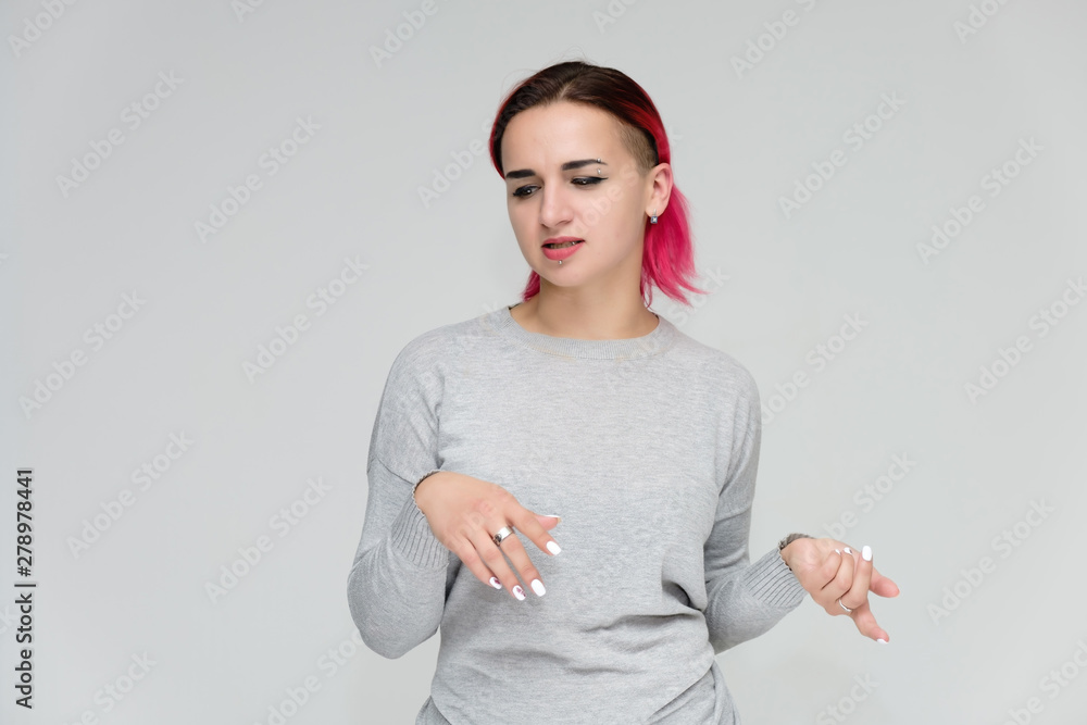 Portrait to the waist of a pretty girl with red hair on a white background in a gray sweater. Standing right in front of the camera in a studio with emotions, talking, showing hands, smiling Portrait to the waist of a pretty girl with red hair on a white background in a gray sweater. Standing right in front of the camera in a studio with emotions, talking, showing hands, smiling