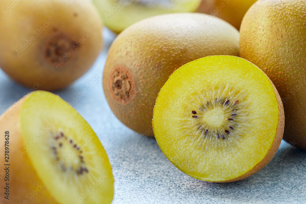 Golden (yellow) organic kiwi. Whole and cut ripe juicy fruits on grey background. kiwifruit. Actinidia chinensis. Selective focus Golden (yellow) organic kiwi. Whole and cut ripe juicy fruits on grey background. kiwifruit. Actinidia chinensis. Selective focus