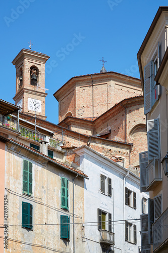 Misericordia church back part in red bricks and old buildings with balcony in a sunny summer day, blue sky in Mondovi, Italy