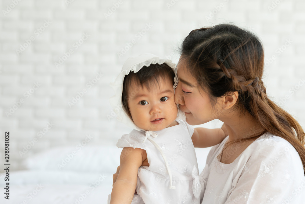 Happy Beauty mother Holding and kissing Cute Sweet Adorable Asian Baby wearing white dress sitting on Carpet smiling and playing with happiness emotional in cozy bedroom,Healthy Baby Concept Happy Beauty mother Holding and kissing Cute Sweet Adorable Asian Baby wearing white dress sitting on Carpet smiling and playing with happiness emotional in cozy bedroom,Healthy Baby Concept