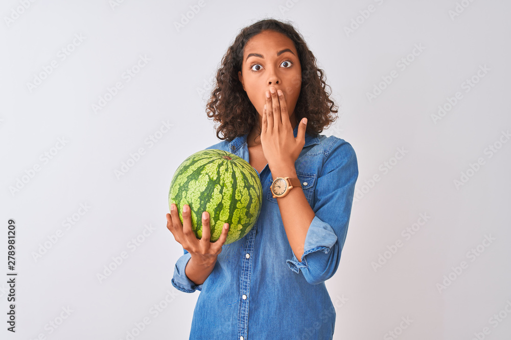 Young brazilian woman holding watermelon standing over isolated white background cover mouth with hand shocked with shame for mistake, expression of fear, scared in silence, secret concept Young brazilian woman holding watermelon standing over isolated white background cover mouth with hand shocked with shame for mistake, expression of fear, scared in silence, secret concept