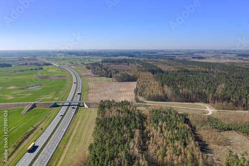 Aerial view of multi-lane highway with moving cars through countryside and forest in summer afternoon. Captured from above with a drone. Poland, A1, Europe. 