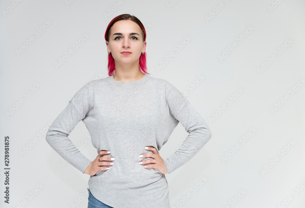 Portrait of a knee-high pretty girl with red hair on a white background in a gray sweater and blue jeans. Standing right in front of the camera with emotions, talking, showing hands, smiling Portrait of a knee-high pretty girl with red hair on a white background in a gray sweater and blue jeans. Standing right in front of the camera with emotions, talking, showing hands, smiling