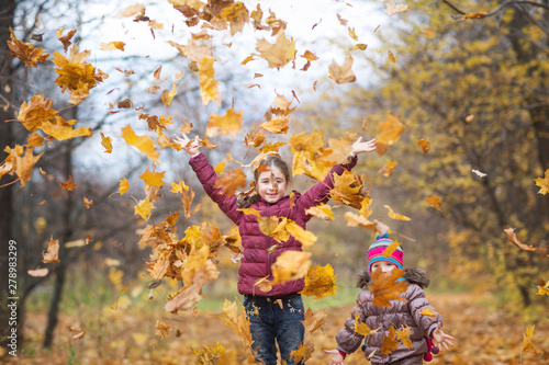happy children. girls throw up autumn yellow leaves on the nature walk outdoors. maple leaf fall in the Park