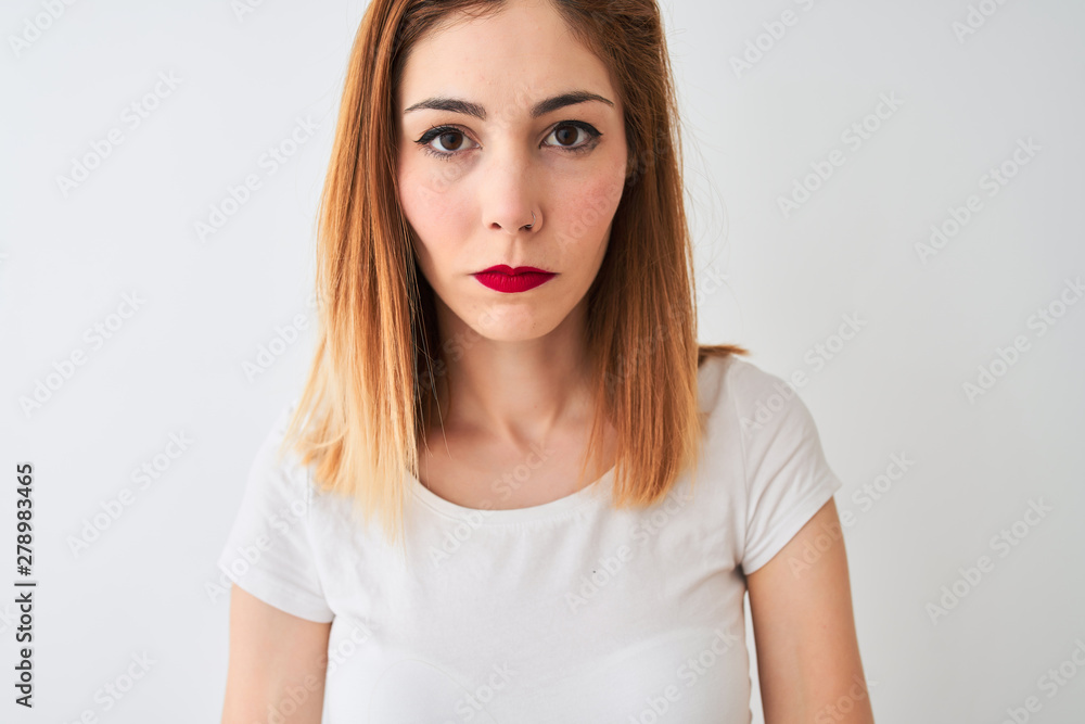 Beautiful redhead woman wearing casual t-shirt standing over isolated white background with a confident expression on smart face thinking serious Beautiful redhead woman wearing casual t-shirt standing over isolated white background with a confident expression on smart face thinking serious