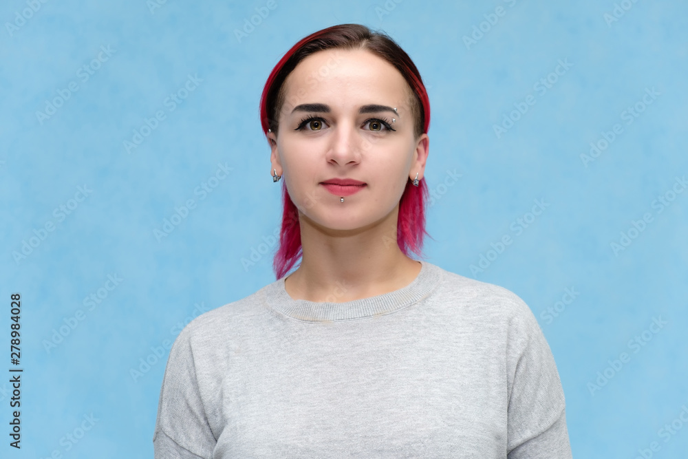 Portrait of the chest of a pretty girl with red hair on a blue background in a gray jacket. Standing in the studio right in front of the camera with emotions, talking, showing hands, smiling Portrait of the chest of a pretty girl with red hair on a blue background in a gray jacket. Standing in the studio right in front of the camera with emotions, talking, showing hands, smiling