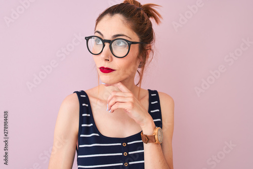 Redhead woman with pigtail wearing striped t-shirt standing over isolated pink background serious face thinking about question, very confused idea